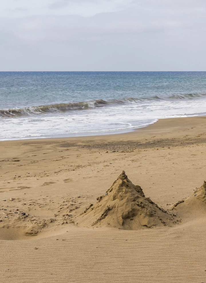 En la imagen aparece el mar de fondo, y la arena en primer plano con una montaña de arena. Es la playa de Matagorda, en Puerto del Carmen (Lanzarote)