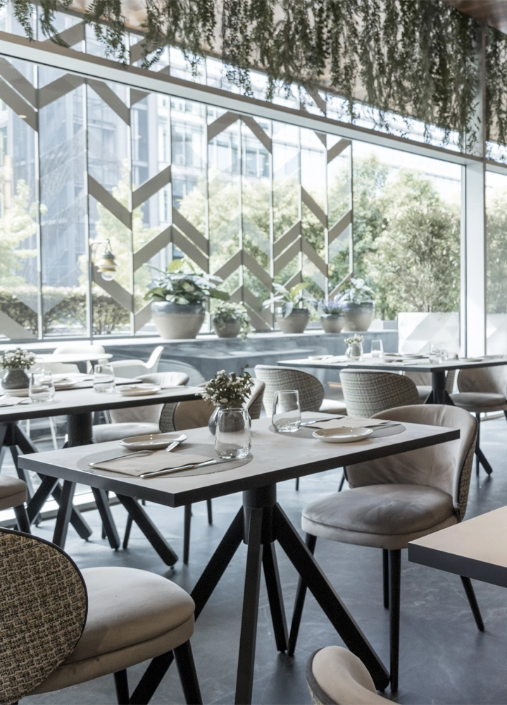 Restaurante moderno con amplios ventanales y mesas de madera, creando un ambiente acogedor y luminoso.